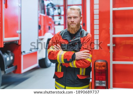 Determined young fire fighter in front of a fire truck in the warden