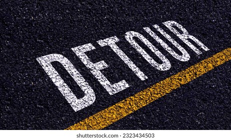 Detour written and yellow line on the road in middle of the asphalt road, Detour word on street.