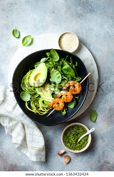 Detox Buddha bowl with avocado, spinach,\
greens, zucchini noodles, grilled shrimps and pesto sauce.\
Vegetarian vegetable low carb lunch bowl.\

