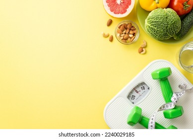 Detox concept. Top view photo of plate with fruits vegetables cabbage cucumber tomato grapefruit nuts glass of water dumbbells tape measure scales on isolated pastel yellow background with copyspace - Powered by Shutterstock