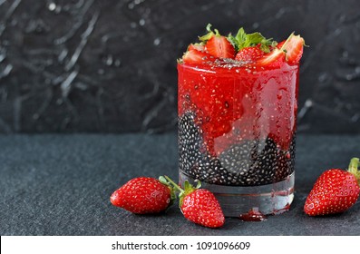 detox food - chia seeds with coal and smoothies from strawberries. useful breakfast with strawberries on a dark background. Wood charcoal detoxification of the body.