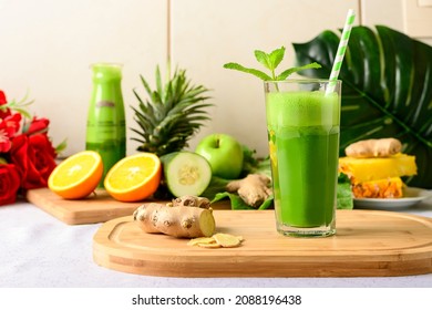 detox green juice, glass with green juice on a wooden board, small fruit ingredient for the juice next to the glass with the drink