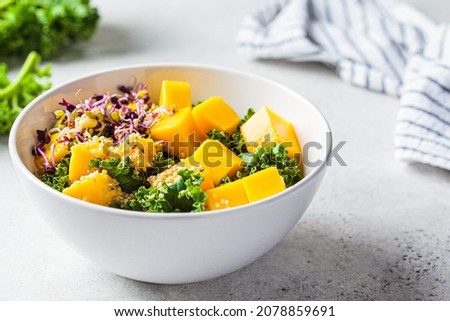 Detox salad with kale, mango and sprouts in a white bowl. Vegan food, healthy plant-based diet concept.