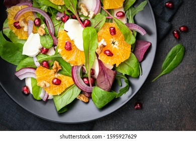 Detox salad with tangerines, mozzarella, herbs, pomegranate seeds and nuts on a dark background. Top view. - Powered by Shutterstock