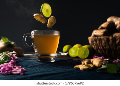 Detox Tea Made Of Ginger Root And Lime With Steam Coming Out Of The Tea Cup And Ingredients Falling Into The Tea. Immune Boosting And Ayurveda Concept. 