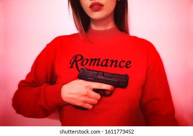 Detroit /USA,1-10-20: A Young Women Holding A Gun Wearing A Romance Shirt. Anti Valentine's Day. Don't Get Stuck In A Bad Romance.