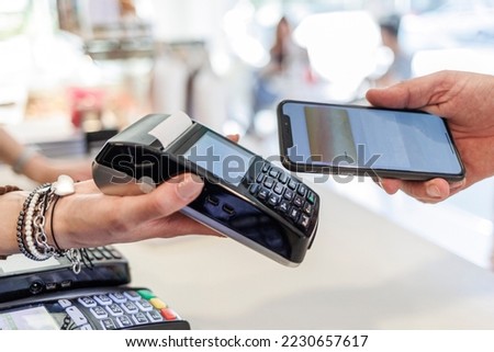Dettaglio del pagamento con carta di credito con uno smartphone verso il pos di tenuto dalla mano di una commessa Stok fotoğraf © 