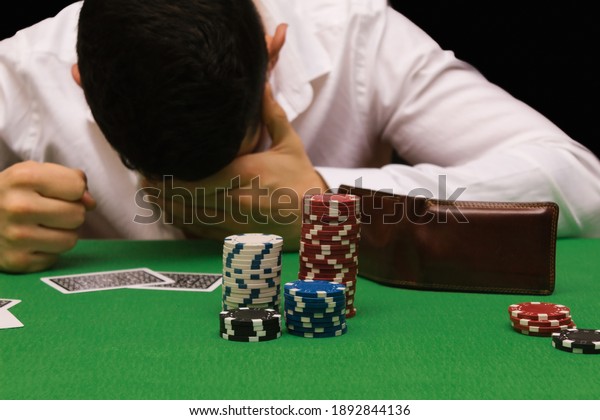 Devastated gambler man losing a lot of money\
playing poker in casino, gambling addiction. Divorce, loss, ruin,\
debt, ludopata\
concept