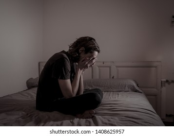 Devastated millennial man crying sad feeling hurt and hopeless suffering Depression. Depressed teenager victim of bullying or abuse sitting on bed alone in despair at night. In teenage Mental health.