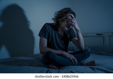 Devastated Millennial Man Crying Sad Feeling Hurt And Hopeless Suffering Depression. Depressed Teenager Victim Of Bullying Or Abuse Sitting On Bed Alone In Despair At Night. In Teenage Mental Health.