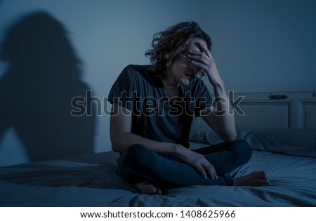 Devastated millennial man crying sad feeling hurt and hopeless suffering Depression. Depressed teenager victim of bullying or abuse sitting on bed alone in despair at night. In teenage Mental health.