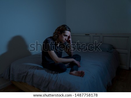 Devastated millennial man crying sad feeling hurt and hopeless suffering Depression. Depressed teenager victim of bullying or abuse sitting on bed alone in despair at night. In teenage Mental health.