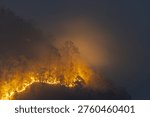 Devastating wildfire smoke spreading across forest mountain at night causing alarming environmental disaster and severe air pollution hazard in northern region destroying natural habitat