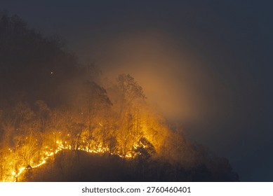 Devastating wildfire smoke spreading across forest mountain at night causing alarming environmental disaster and severe air pollution hazard in northern region destroying natural habitat