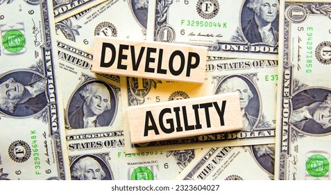 Develop agility symbol. Concept words Develop agility on wooden blocks on a beautiful background from dollar bills. Dollar bills. Business, support and develop agility concept. Copy space. - Shutterstock ID 2323604027