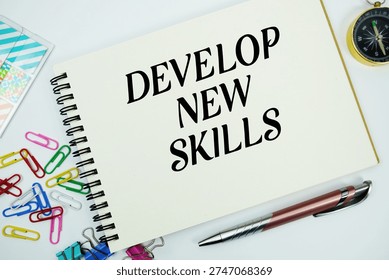 Develop New Skills text message written on notepad with stationery flat lay on white background
