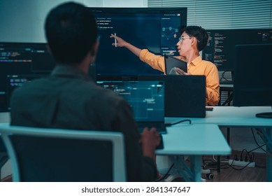 Developer presents software analytics on large screens during a collaborative office technology meeting