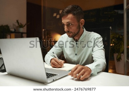 Developer reading article on laptop and taking notes
