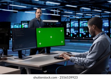 Developer in server room checking recovery plan and monitoring energy consumption using isolated screen PC. Employee in data center workplace doing disk checks using chroma key computer