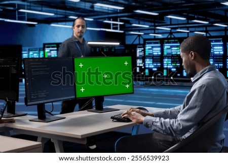 Developer in server room checking recovery plan and monitoring energy consumption using isolated screen PC. Employee in data center workplace doing disk checks using chroma key computer