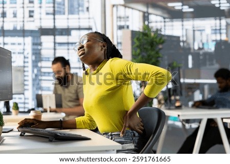 Developer suffering backpain from bad posture on office chair while fixing applications issues. Fatigued IT expert feeling muscle strain while optimizing company software for improved performance