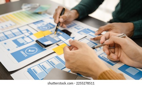 developer and ui designer brainstorming about mobile app interface wireframe design with customer breif and color code at office.