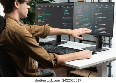 IT developer working online software development on pc monitors at modern home office on coding application screens, creating updated latest program firmware information version concept. Gusher.