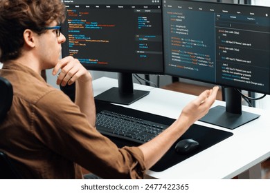 IT developer working online software development on pc monitors at modern home office on coding application screens, creating updated latest program firmware information version concept. Gusher. - Powered by Shutterstock