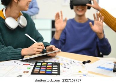 Developers team brainstorming, testing virtual reality simulator glasses at meeting, future technology for business concept