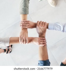 Developing a good work ethic is key. Cropped shot of a group of businesspeople linking their arms in solidarity at work.
