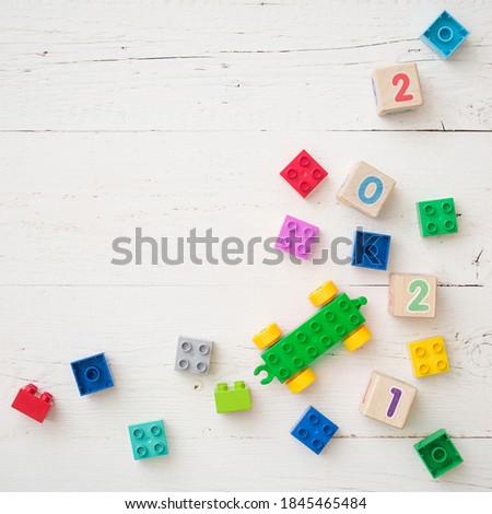 Developing multi-colored cubes on a white wooden table. Wooden cubes with numbers 2021 and others. Top view of the numbers of the year and other educational toys.