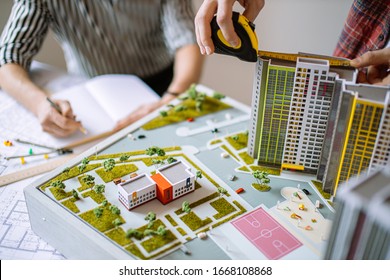 developing new building project with the use of blueprints and notes. professional workers, experts, engineers and architects have high-rise building model, they design new residential according it