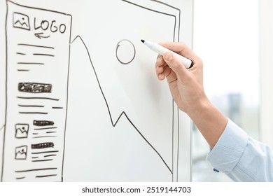 Developing UI design. Man drawing website wireframe on whiteboard indoors, closeup