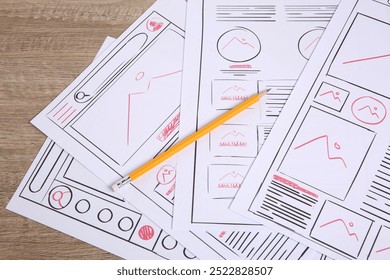 Developing UI design. Sketches of website wireframes and pencil on wooden table, closeup