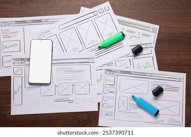 Developing UI design. Sketches of website wireframes, smartphone and felt pens on wooden table, top view