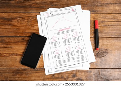 Developing UI design. Sketches of website wireframes, felt pen and smartphone on wooden table, top view