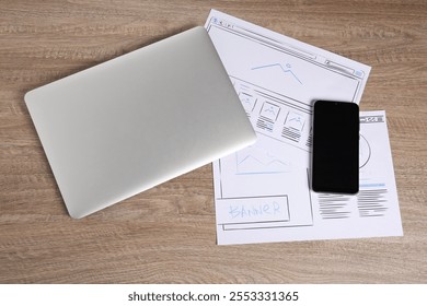Developing UI design. Sketches of website wireframes, laptop and smartphone on wooden table, top view