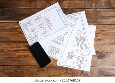 Developing UI design. Sketches of website wireframes and smartphone on wooden table, top view