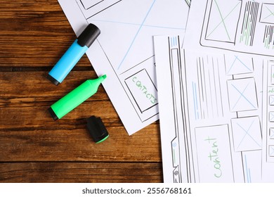 Developing UI design. Sketches of website wireframes and felt pens on wooden table, top view