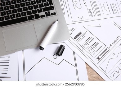 Developing UI design. Sketches of website wireframes, laptop and felt pen on wooden table, above view