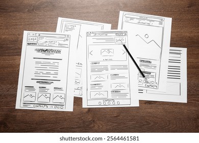 Developing UI design. Sketches of website wireframes and pencil on wooden table, top view