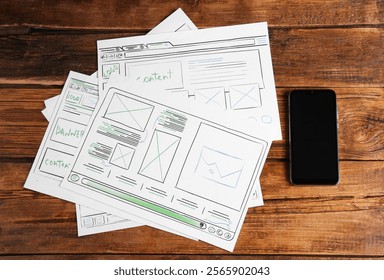 Developing UI design. Sketches of website wireframes and smartphone on wooden table, top view