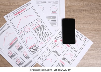 Developing UI design. Sketches of website wireframes and smartphone on wooden table, top view