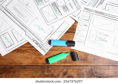 Developing UI design. Sketches of website wireframes and felt pens on wooden table, top view