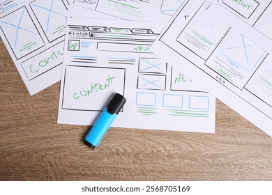 Developing UI design. Sketches of website wireframes and felt pen on wooden table, top view