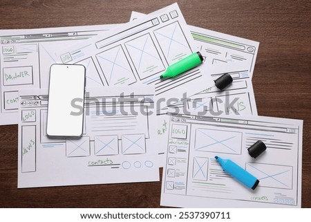 Developing UI design. Sketches of website wireframes, smartphone and felt pens on wooden table, top view