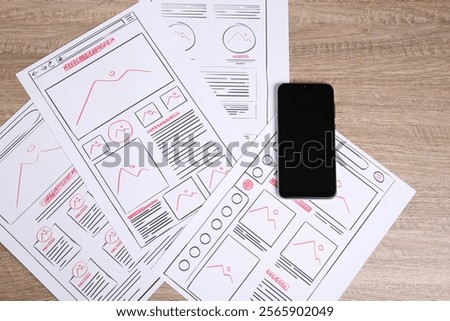 Developing UI design. Sketches of website wireframes and smartphone on wooden table, top view