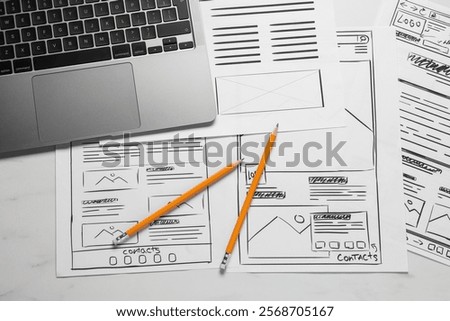 Developing UI design. Sketches of website wireframes, laptop and pencils on white marble table, top view