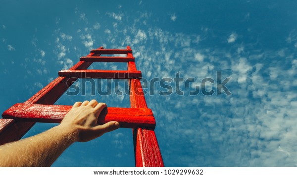 Development Attainment\
Motivation Career Growth Concept. Mans Hand Reaching For Red Ladder\
Leading To A Blue\
Sky
