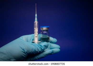 Development of coronavirus vaccine COVID-19. bottle phial with no label and medical syringe with injection needle in blue medical glove. isolated on blue background. cure. copy space